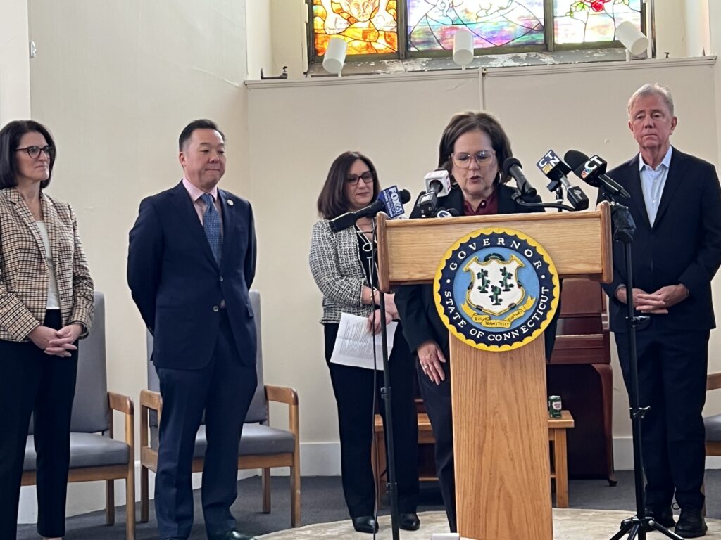 DMHAS Commissioner Nancy Navarretta speaking at a podium with the State of Connecticut seal.